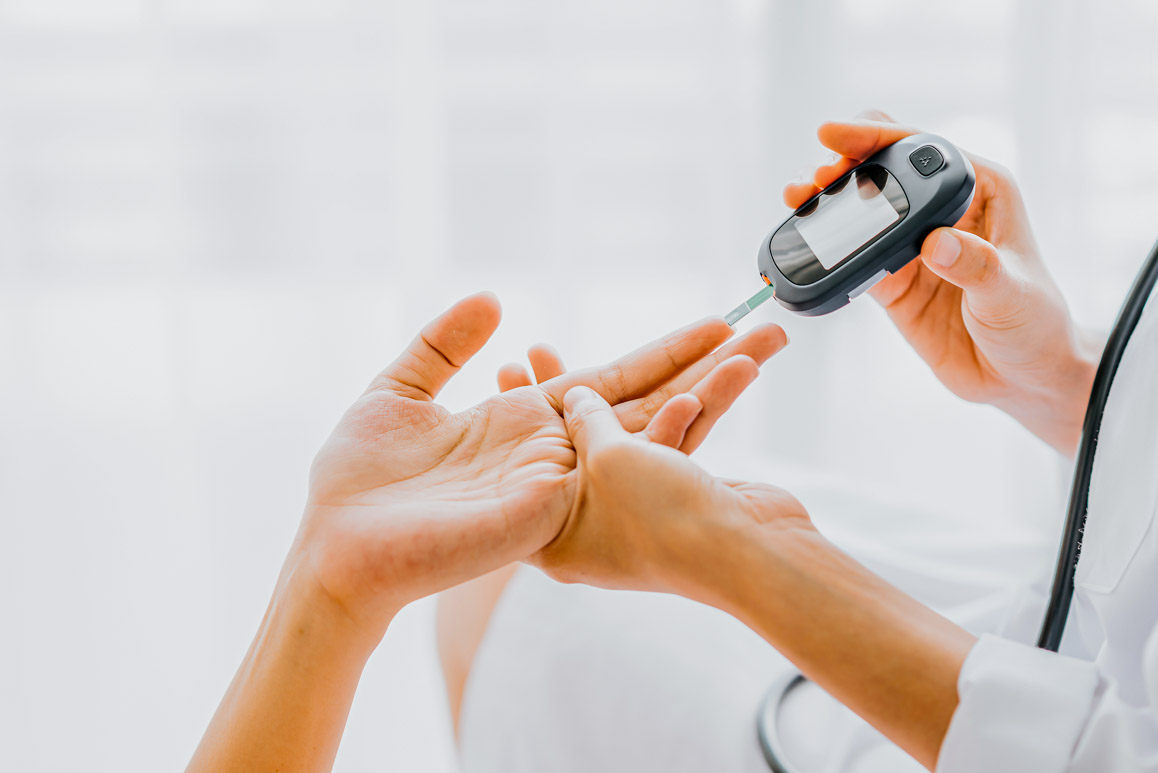 Doctor use glucosmeter checking blood sugar level from patient hand