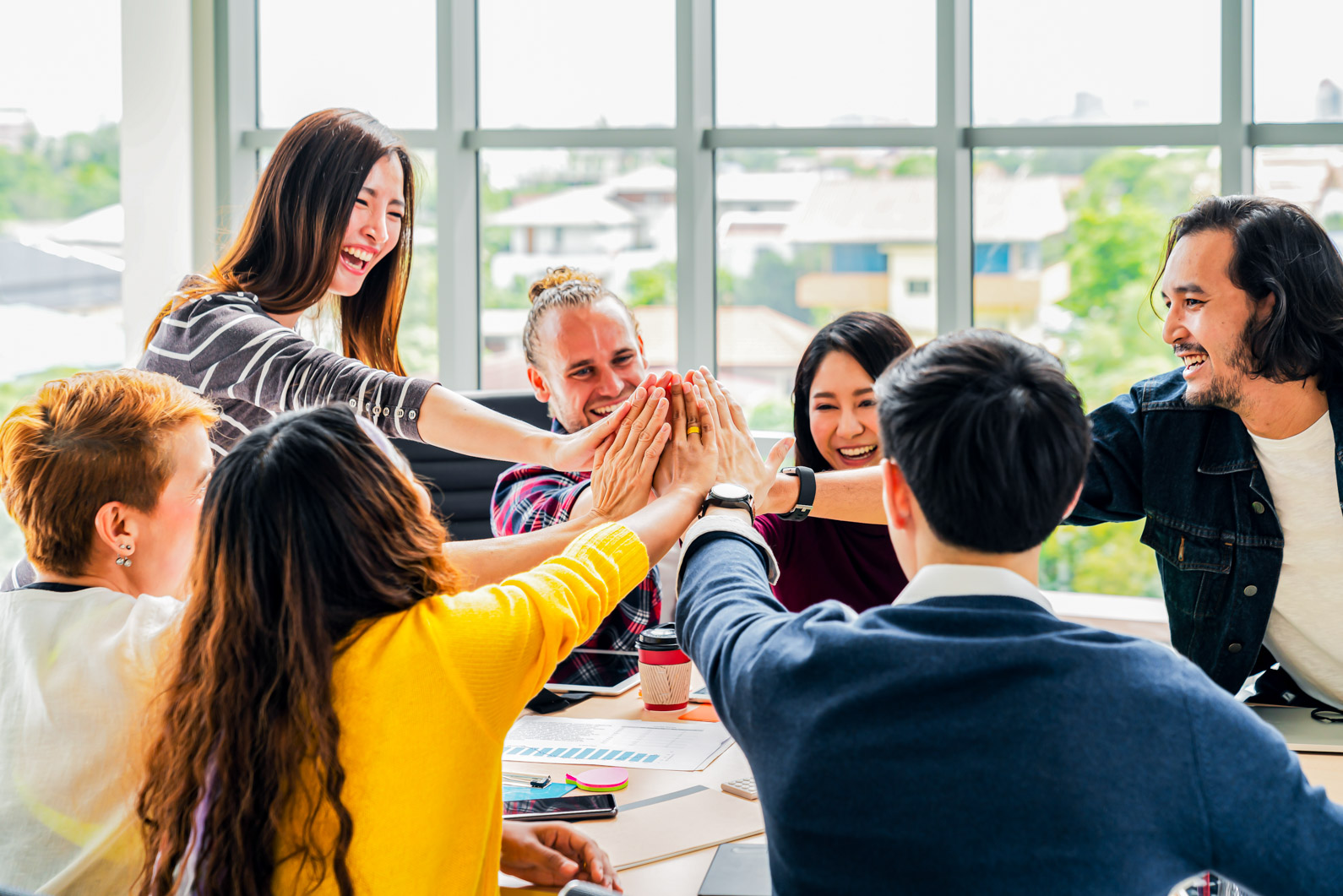 group of young multiethnic diverse people gesture hand high five, laughing and smiling together in brainstorm meeting at office. Casual business with startup teamwork community celebration concept.